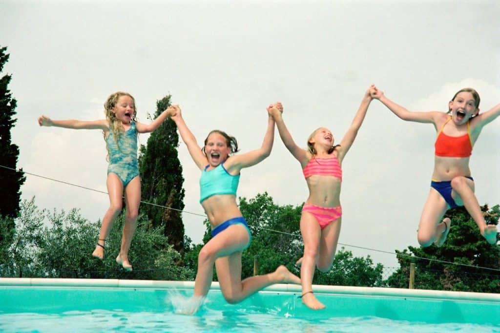 girls jumping into swimming pool