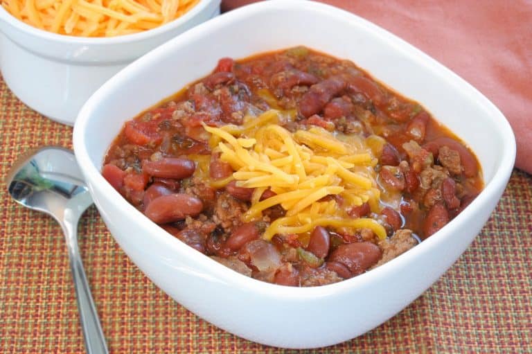 Homemade chili with beef and beans, garnished with shredded cheddar cheese