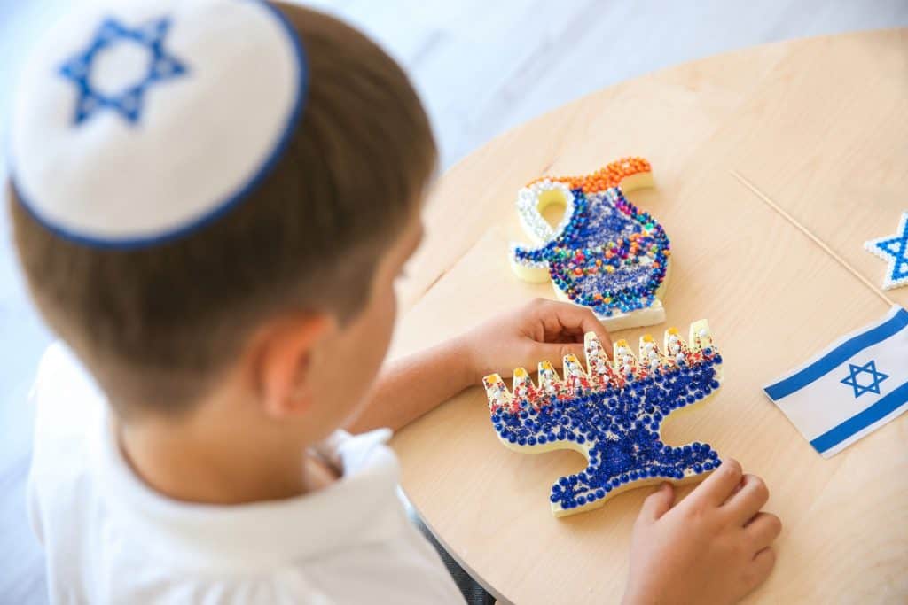 Boy with handmade nine-branched menorah at home