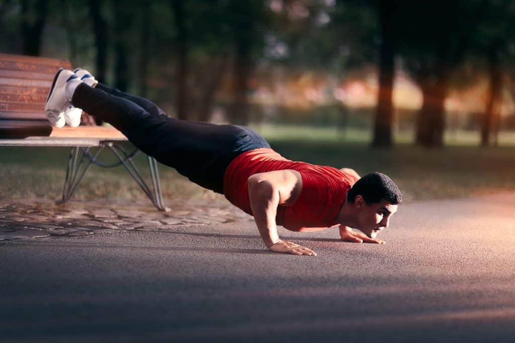 man doing calesthenics using a park bench