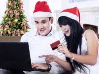 A couple wearing Santa hats shopping online