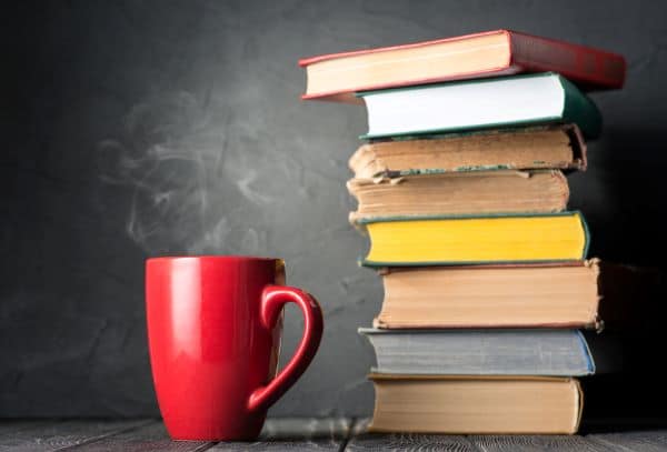 cup of steaming coffee and a stack of old books