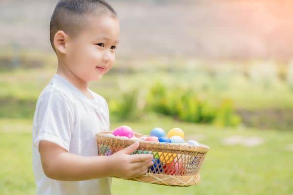 young boy with a basket of colorful easter eggs