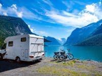 RV camper and bikes parked by a mountain lake