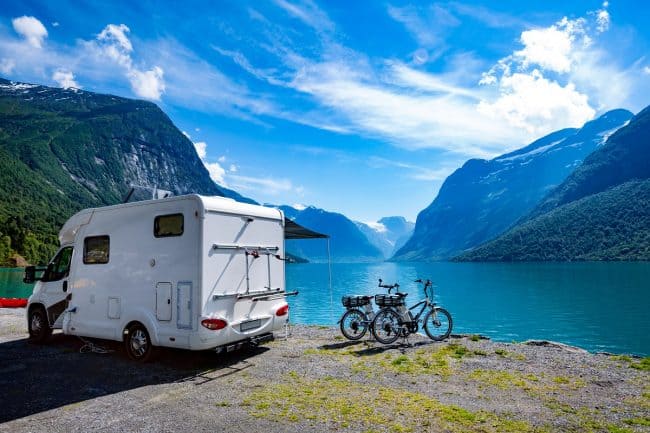 RV camper and bikes parked by a mountain lake