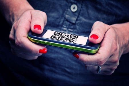 woman holding smartphone with QR code visible