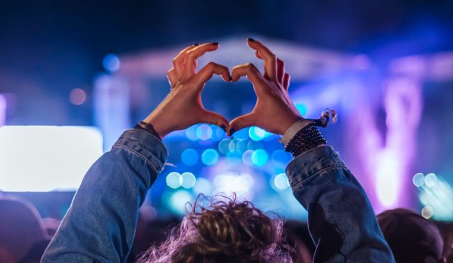 woman making a heart shape with her hands at a live music performance