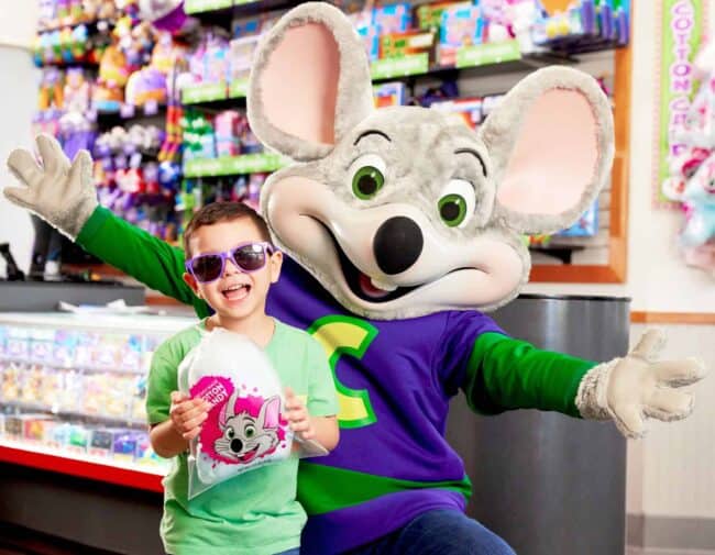 Young boy with a mouse character at Chuck E. Cheese