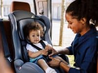 mom fastening child in car seat